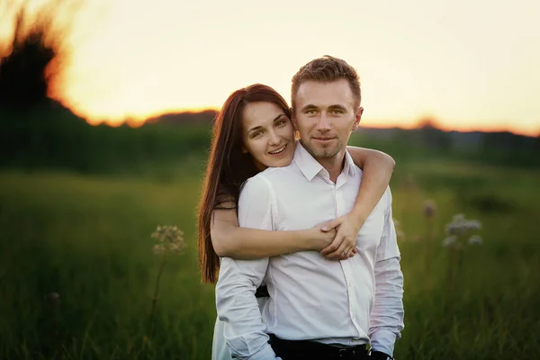 夏の日の日没には若い夫婦が野外で抱き合っています ロマンチック 人々の概念 愛の物語 — ストック写真