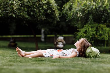 Şirin küçük kız gülüyor ve çimde lahana ile yatıyor. Anneler Günü, aşk ailesi, ebeveynlik, çocukluk kavramı.