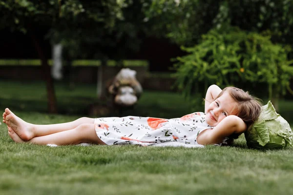 Мила дівчинка сміється і лежить на траві з капусти. День матері, сім'я, батьківство, дитинство.. — стокове фото