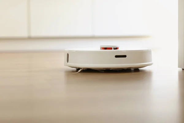 リビングルームのインテリアでラミネートフロアクリーニングほこり上の白いロボット掃除機 スマート電子ハウスキーピング技術 スマートホーム — ストック写真