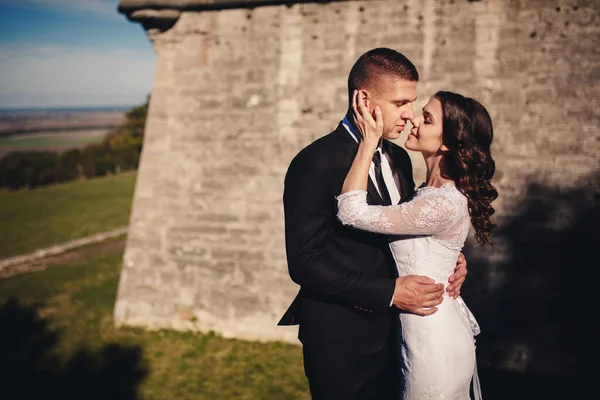 Eski kale duvarının yanında poz veren yeni evli çift, antik kale açıklarında peri masalı düğünü, gelin ve damadın kale kulesinin yanında kucaklaşması, düğün anı..