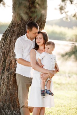 Baba, anne oğlunu parkta kucaklıyor. Yaz tatili kavramı. Anneler günü, babalar günü, bebekler günü. Aile doğada birlikte vakit geçiriyor. Aile görünüşü. seçici odak.