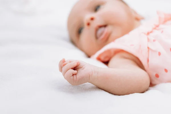 Bébé fille nouveau-né sur l'herbe dans le parc à l'extérieur, se trouve sur une couverture blanche regardant autour. focus sélectif. — Photo