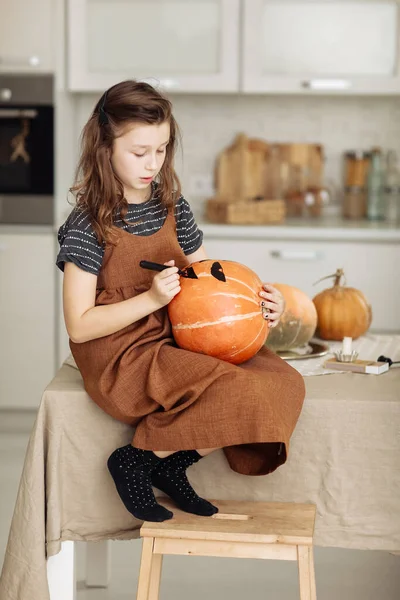 little girl paints a pumpkin for Halloween. preparation for halloween. Halloween holiday and family lifestyle background. selective focus.
