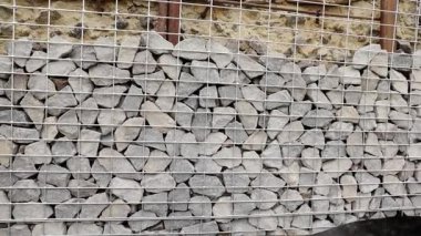 Çelik örgü ve duvar örülü taş çitler. Gabion 'u sıkıca paketlenmiş, değişik boyutlarda ve dokularda taşlarla kapatın. Doğal malzemelerin ve endüstriyel tasarımın kombinasyonu