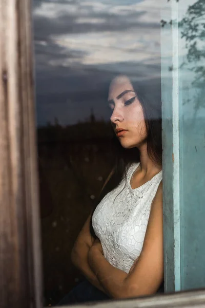 girl by the window in a wooden old abandoned house with dim light
