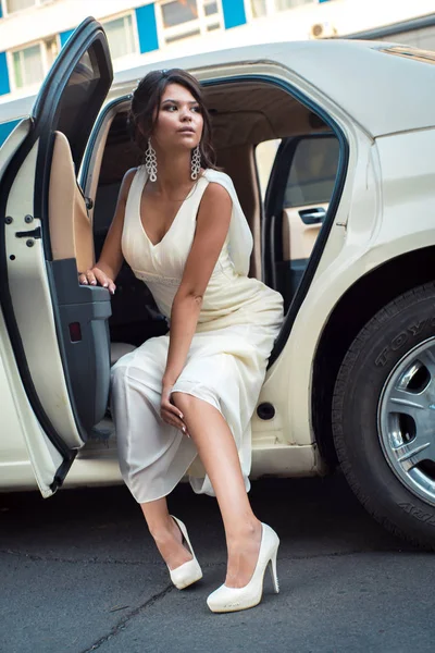 Young attractive VIP Woman getting out of limousine with door being open
