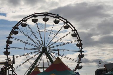 Uğursuz fırtına bulutları yatay arka plan ile bir karartma karşı mavi siluet gökyüzünde boş dönme dolap ve bölge Panayırı gölgelik çadır