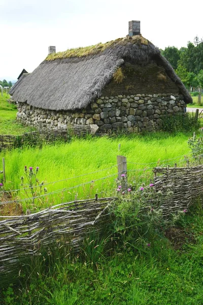 Sazlı çatısı ve kırsal İskoç dağlarında dokuma çiti olan geleneksel taş kulübe.