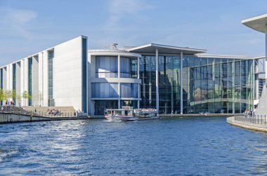 Berlin, Almanya - 22 Nisan 2018: Nehir Spree turist tekneleri ve Paul-Loebe House renkli cam yansıtan onun cephesi ile yeni bina Parlamento ile