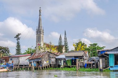 Cai, Vietnam - 6 Nisan, 2018: su sümbül tarafından işgal Mekong Nehri kıyısında birini doğaçlama gövdeleri ve hovels ve Cai neo-gotik Katedrali ile olmak bir nehir kara karışık şehir Mekong Deltası'nda