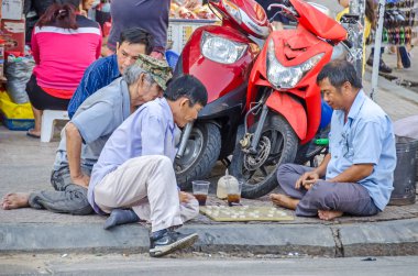 Ho Chi Minh City, Vietnam - 4 Nisan, 2018: Street scene - erkekler Park edilmiş mopedler ve Pazar standları arasında şehir merkezinde crossways adlı geleneksel masa oyunu oynamak
