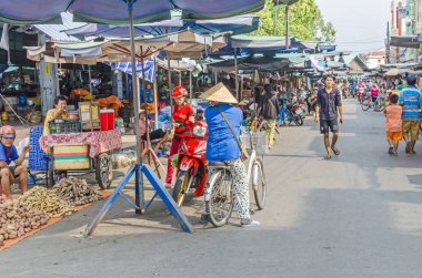Cai, Vietnam - 6 Nisan 2018: Pazar Cai olması, yerli sebze ve onların bisiklet, mopedler ve motosiklet üzerinde pazar ziyaret müşteriler satış ile Mekong Deltası'nda bir nehir-arazi karışık kasabada tipik Vietnamca Pazar