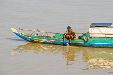 Phnom Penh, Kamboçya - 9 Nisan 2018: Tipik uzun kuyruk Kamboçyalı Mekong tekne bir gölgelik ve üzerinde bir erkek çocuğunu yıkama yaşayan bir aile ile