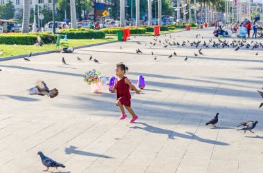 Phnom Penh, Kamboçya - 9 Nisan 2018: Preah Sisowath Quay, onun büyük, uzun açık alan ve güvercinler sonra kaçan bir genç kız ile Tonle Sap nehir kıyısında bir nehir genel mesire