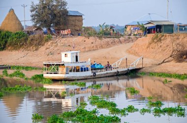 Siem Reap, Kamboçya - 10 Nisan 2018: Bir köy Tonle Sap Gölü invaziv su sümbül ve geç akşam mal ve yolcu taşıma bir feribot tekne ile kaplı