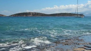 Dalgalar küçük bir defne, mavi su, güneşli bir gün, ufukta bulutlar küçük bir ada arka planı üzerinde sallanan beyaz Yelkenli Yat