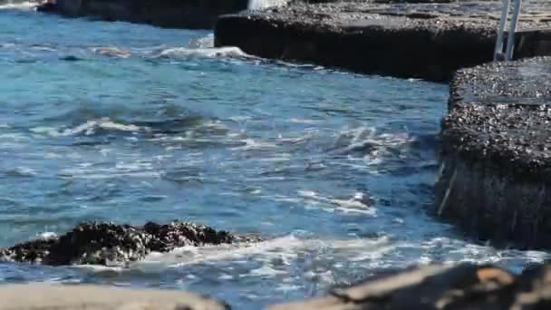 在一个安静的阳光明媚的日子里 温暖的大海的浪花拍打在岸边 溅起了水 — 图库视频影像