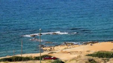 Otel penceresinden deniz manzarası, açık mavi deniz, açık esinti, kumlu plaj. Sahil boyunca ATVs ve araba sürücü.