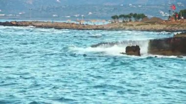 Fırtına öncesinde denizin akşam manzarası, bir sürü hareket, mavi dalgalar, beyaz köpük ve sıçramalar, bayraklar güçlü rüzgarda evrim