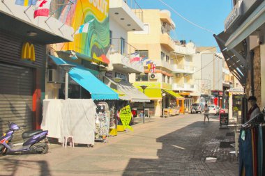 Chersonissos, Girit, Yunanistan, 10/18/2015, açıklayıcı editoryal tatil beldesi sokakları, dükkanlar, restoranlar ve renkli parlak işaretler, yüksek kontrast, güneşli sabah, mavi gökyüzü ile küçük bir sokak