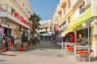 Chersonissos, Girit, Yunanistan, 10/18/2015, açıklayıcı editoryal tatil beldesi sokakları, dükkanlar, restoranlar ve renkli parlak işaretler, yüksek kontrast, güneşli sabah, mavi gökyüzü ile küçük bir sokak