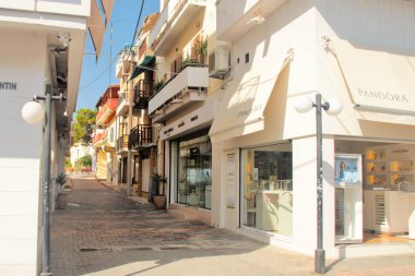 Chersonissos, Girit, Yunanistan, 10/18/2015, açıklayıcı editoryal tatil beldesi sokakları, dükkanlar, restoranlar ve renkli parlak işaretler, yüksek kontrast, güneşli sabah, mavi ile küçük bir sokak 