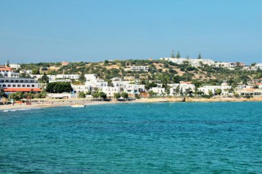 Akdeniz 'de tatil kenti, plaj ve deniz plajdaki oteller görünümü. Parlak güneş ışığı, berrak mavi deniz, yüksek kontrast. Girit, Chersonisou.