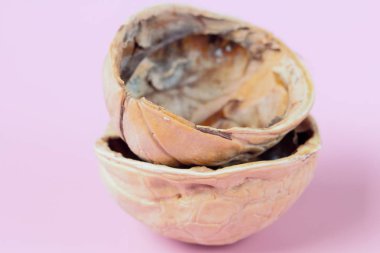 Bir ceviz kabuğu yakın çekim, pembe arka plan, yüksek kontrast iki yarısı.