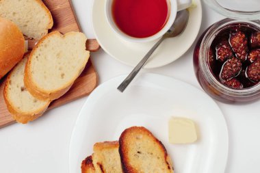 Basit bir tatlı kahvaltı için ayarlayın, tost baget, çay, tereyağı, çam kozalağı reçel. Parlak renkler, yüksek kontrast, beyaz arka plan.