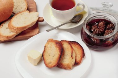 Basit bir tatlı kahvaltı için ayarlayın, tost baget, çay, tereyağı, çam kozalağı reçel. Parlak renkler, yüksek kontrast, beyaz arka plan.