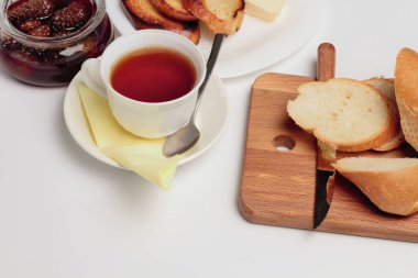 Basit bir tatlı kahvaltı için ayarlayın, tost baget, çay, tereyağı, çam kozalağı reçel. Parlak renkler, yüksek kontrast, beyaz arka plan.