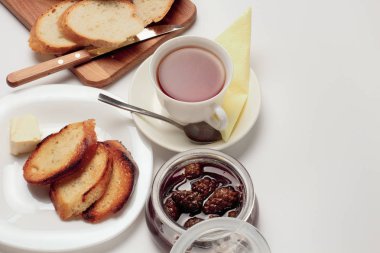 Basit bir tatlı kahvaltı için ayarlayın, tost baget, çay, tereyağı, çam kozalağı reçel. Parlak renkler, yüksek kontrast, beyaz arka plan.