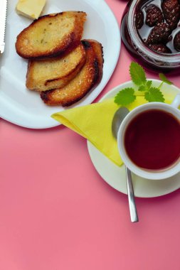 Bir kopya alanı, çay, tost ekmek, reçel, yüksek kontrast, parlak renkler, üst görünümü ile pembe bir arka plan üzerinde basit bir tatlı kahvaltı için ayarlayın.