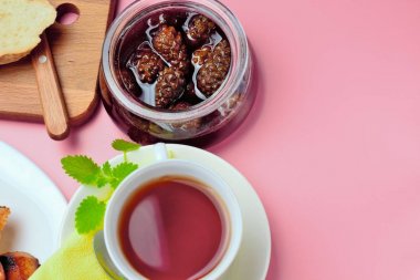Basit bir tatlı kahvaltı için ayarlayın, tost baget, çay, tereyağı, çam kozalağı reçel. Parlak renkler, yüksek kontrast, pembe arka plan.