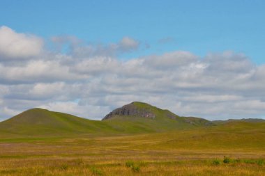 Tepeler ve mavi gökyüzü, yüksek kontrast, parlak renkler ile doğal bozkır manzara.