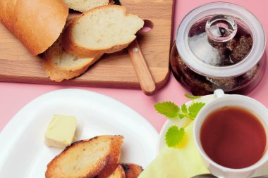 Basit bir tatlı kahvaltı için ayarlayın, kızarmış ekmek, çay, reçel, pembe bir arka plan üzerinde.