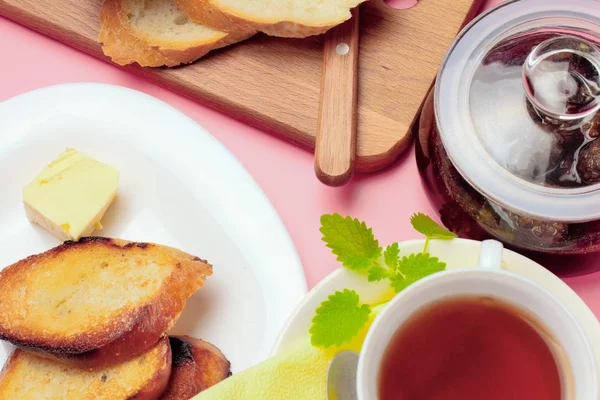 Basit bir tatlı kahvaltı için ayarlayın, kızarmış ekmek, çay, reçel, pembe bir arka plan üzerinde.