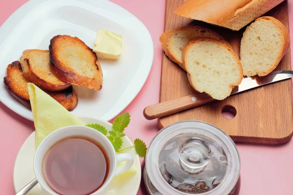 Basit bir tatlı kahvaltı için ayarlayın, kızarmış ekmek, çay, reçel, pembe bir arka plan üzerinde.
