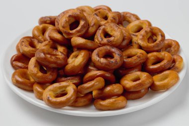 Açık arka plan, parlak renkler, yüksek kontrastlı, yakın çekim beyaz bir plaka üzerinde gevrek simitler iştah açıcı slaytlar.