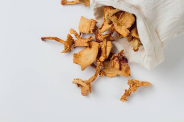 Beyaz bir arka plan üzerinde dağınık bir bez kese kurutulmuş chanterelle mantar, yer fot metin. Doğal renkler, yüksek kontrast.