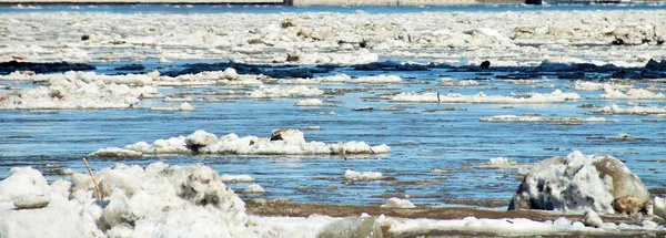 Floating of ice on the river, blocks of old ice float during the freezing season. High contrast, bright colors, wide panorama.