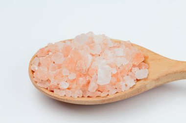 Beyaz arka plan yakın çekim, doğal parlak renk, yüksek kontrast üzerinde tahta bir kaşık pembe Himalaya tuzu.