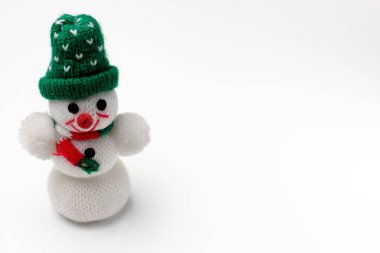 Beyaz arka plan üzerinde yeşil bir kap Noel yumuşak oyuncak kardan adam, yakın çekim, metin için alan, parlak renkler.