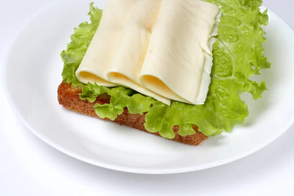 Veggie sandwich with lettuce and pieces of cheese on a large plate on a white background, bright natural colors.