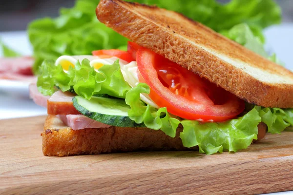 Sandwich Con Jamón Lechuga Rebanadas Queso Tomates Una Tabla Cortar — Foto de Stock