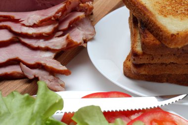 Kavrulmuş ekmek, peynir, jambon, sebze ve yeşillik ile bir sandviç yapmak için bir ürün kümesi. Beyaz arka plan ve koyu renk kesme tahtası.