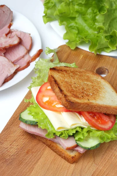 Sandwich Med Skinka Sallad Skivor Ost Tomater Skär Bräda Vit — Stockfoto