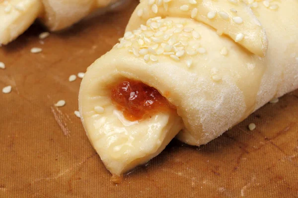 Homemade croissants with apricot jam and sesame close-up on a baking tray