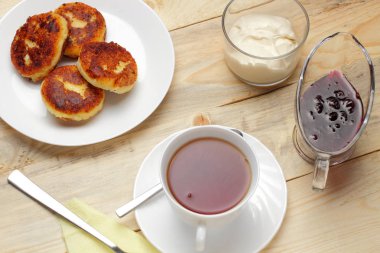 Doğal ahşap bir arka plan üzerinde reçel ve ekşi krema ile Peynir kek, hızlı ve lezzetli kahvaltı rustik bir versiyonu